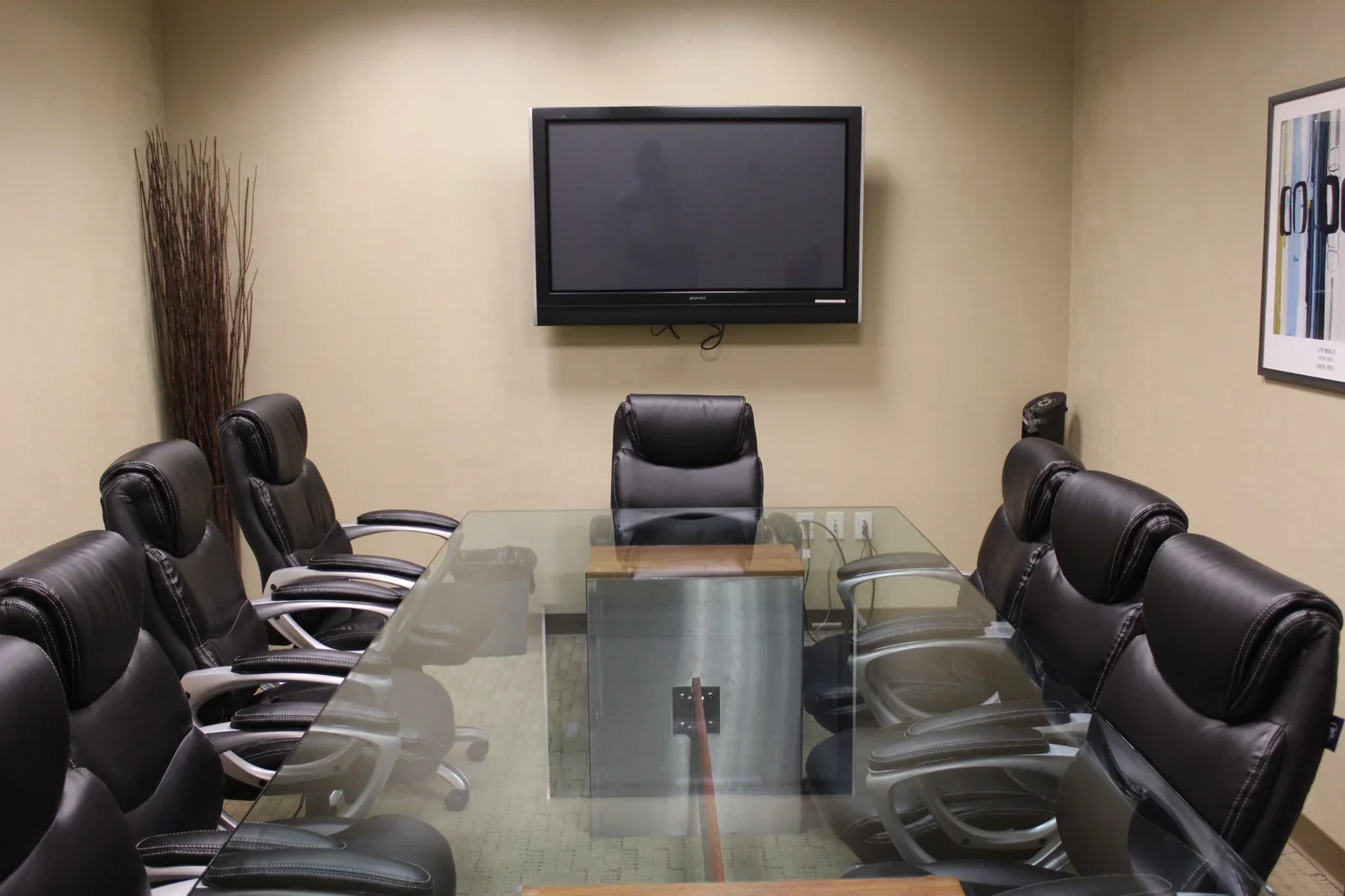 Large conference room viewed along the glass table toward a wall-mounted display.