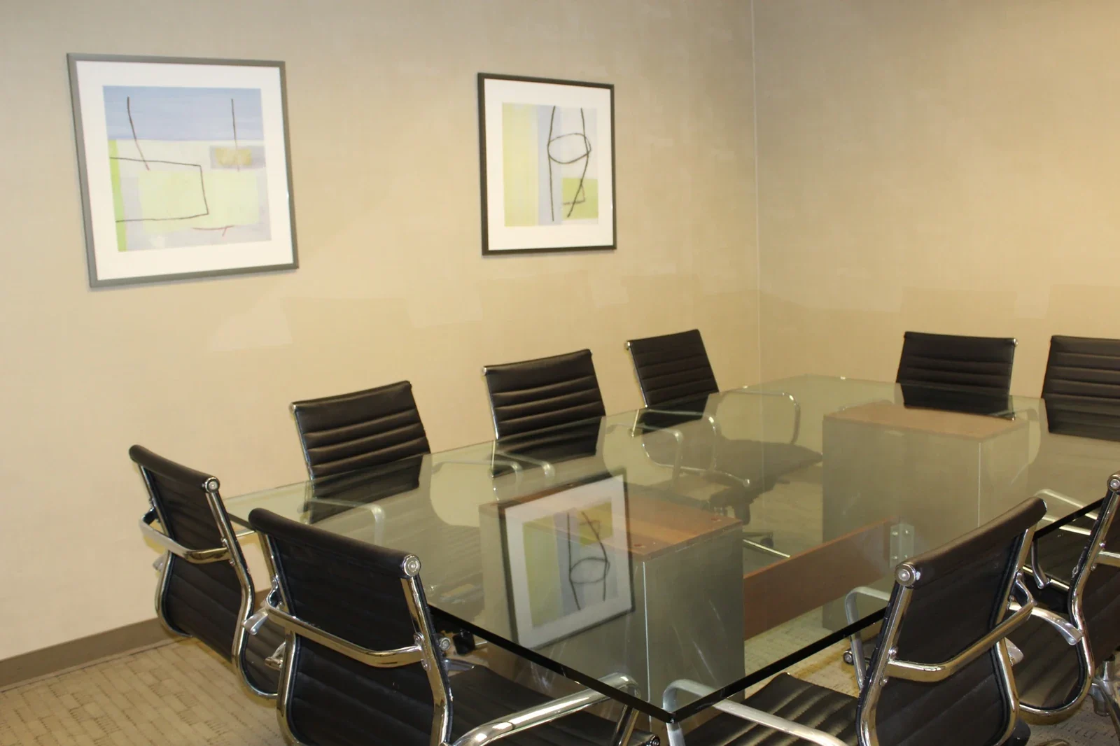 Meeting table surrounded by black ribbed chairs beneath wall artwork.