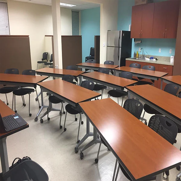 Training room with rows of tables, chairs and kitchenette along the rear.